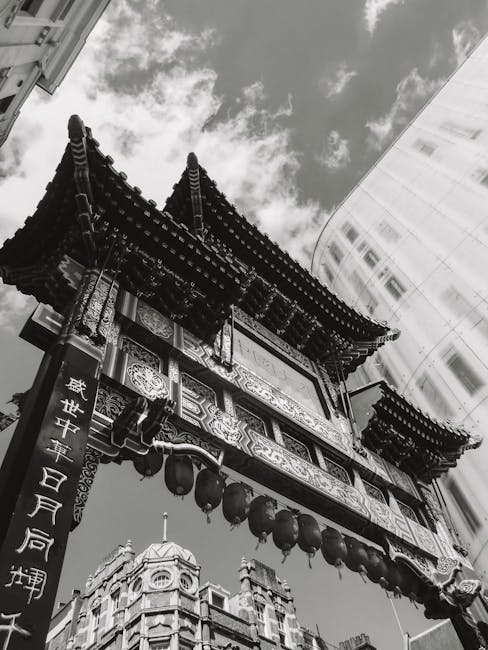 A black-and-white photograph captured from below shows a traditional Chinese architectural structure situated on a rooftop garden in Leicester Square, featuring ornate curved eaves with detailed carvi